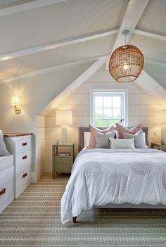 a bed sitting under a window in a bedroom next to a white dresser and chair