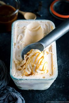 a scoop of ice cream with caramel drizzled on top, in a glass container