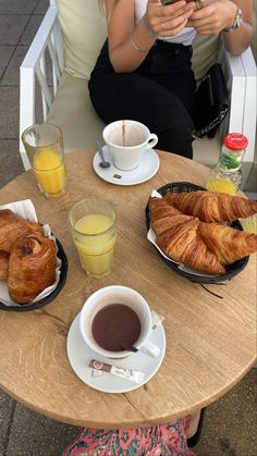 a woman sitting at a table with coffee, croissants and orange juice