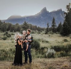 a family standing in the grass with mountains in the background