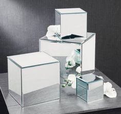 three mirrored cubes with flowers in them on a table next to a mirror box