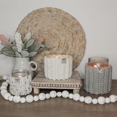 some candles are sitting on a table next to a vase with flowers and other items