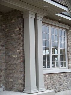 a brick house with white trim and windows on the front porch, next to a red fire hydrant