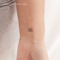 a small tattoo on the wrist of a woman's left hand, depicting an eye