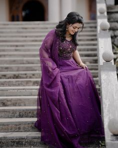 a woman in a purple dress sitting on some steps