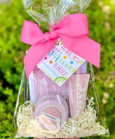 a pink gift basket with personal care items in it and a ribbon tied around the top