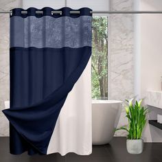 a blue and white shower curtain next to a bathtub with a plant in it