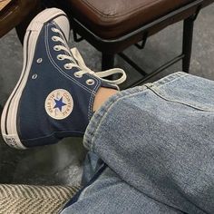 a person sitting on a chair with their legs crossed and wearing blue converse shoes,