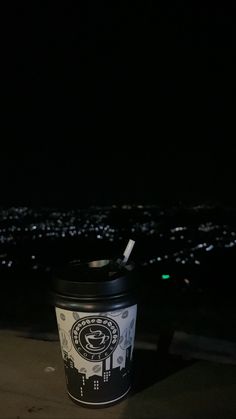 a cup with a straw in it sitting on top of a roof at night time