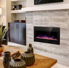 a living room with a fire place in the center and two vases on the coffee table