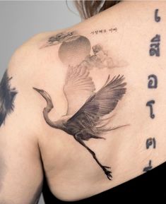 the back of a woman's shoulder with a bird tattoo on her left side