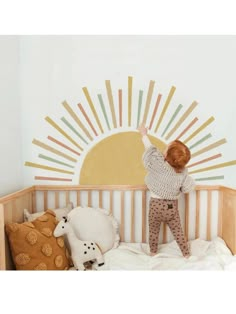 a little boy that is standing in a crib with some stuffed animals on it