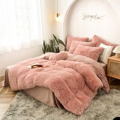 a bed with pink comforter and pillows in a room