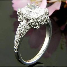 a close up of a diamond ring with flowers in the background