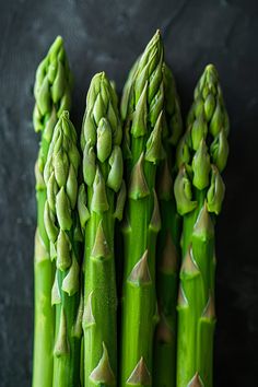 Fresh green asparagus spears arranged upright against a dark background. Sauteed Asparagus Recipes, Healthy Asparagus Recipes, Sauteed Asparagus