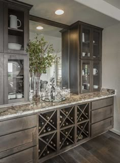 a kitchen with wooden cabinets and marble counter tops, along with a wine glass cabinet