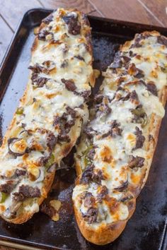 two long pieces of bread with cheese and meat on it sitting on a baking sheet