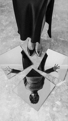 a black and white photo of a woman's legs in the middle of three mirrors