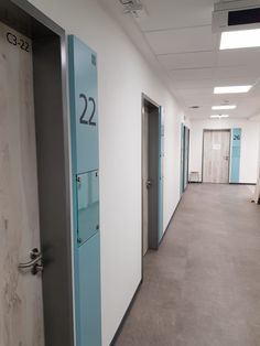 an empty hallway with blue doors and numbers on the door, leading to another room