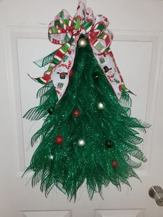 a green christmas tree hanging on the front door