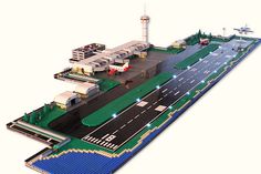 a lego model of an airport with cars and trucks on the runway next to it