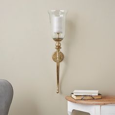 a wall light with a candle on it next to a chair and table in a room