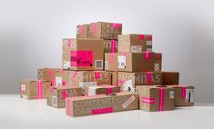 several cardboard boxes stacked on top of each other with pink tape around the edges and labels