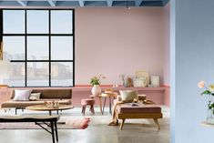 a living room with pink walls and furniture in front of a large window that overlooks the city