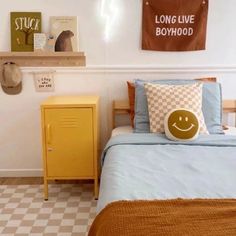 a bed room with a neatly made bed next to a yellow cabinet and wall hangings