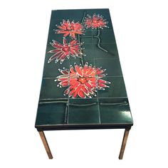 a green table with red flowers on the top and legs, against a white background