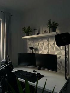 a computer desk with two monitors and a keyboard on it in front of a window