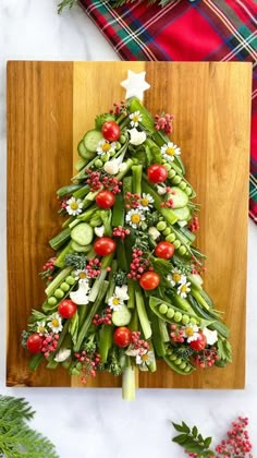 a christmas tree made out of vegetables on a cutting board next to other holiday decorations