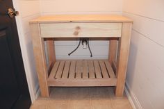 a small wooden table sitting in the corner of a room next to a door with a handle on it