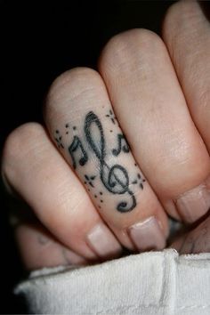 a person's hand with a musical note tattoo on their thumb and ring finger