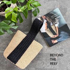 a crocheted purse sitting on top of a book next to a potted plant