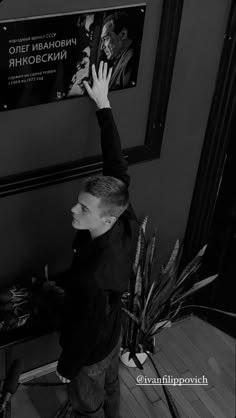 a young man reaching up to grab something off the wall in front of him with his hands