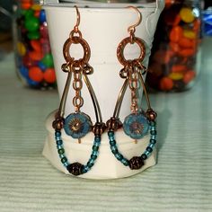 This Design Started Out With A Brass Wire Long Loop Attached To A Beautiful Copper Hammered Ring. I Added Several Beads Of Frosted Teal, & Green, & Baby Blue. Separated With A Copper Barrel Bead And Copper Findings On Both Sides. A Copper Chain Dangles A Pretty Blue Flower From The Center. I Used Copper Ear Wires. I Love This Look! One Of A Kind All Handcrafted By Me. Ugly Jewelry, Hammered Wire Jewelry, Czech Beads Jewelry, Creative Earrings, Wire Jewelry Earrings, Earrings Diy Handmade, Silver Chandelier Earrings, Earrings Ideas, Flower Dangle Earrings