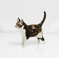 a cat figurine is standing on a white surface and looking at the camera