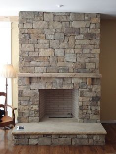 an empty living room with a stone fireplace