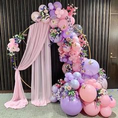 a balloon arch with balloons and flowers on it