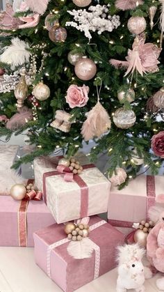 a christmas tree decorated with pink and gold ornaments next to two small presents under it