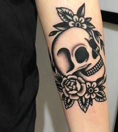 a woman with a skull and flower tattoo on her arm