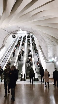 many people are walking up and down the escalator in an underground subway station