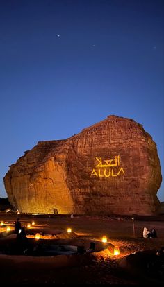 people sitting in front of a large rock with the word abua written on it