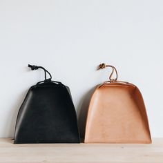 two black and brown purses sitting on top of a wooden shelf next to each other