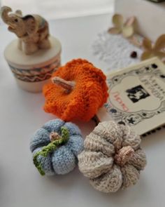 small crocheted pumpkins sitting on top of a table next to a book