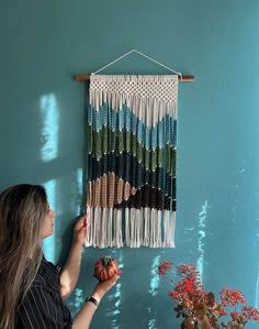 a woman is working on a wall hanging