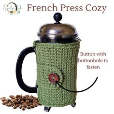 a crocheted coffee mug cozy with buttons on the front and bottom is shown