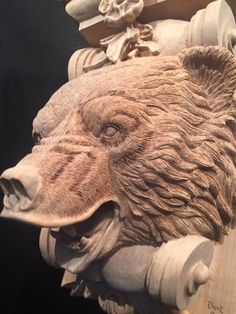 a carving of a bear's head on the side of a wooden wall hanging