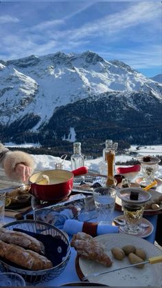 a table full of food with mountains in the background